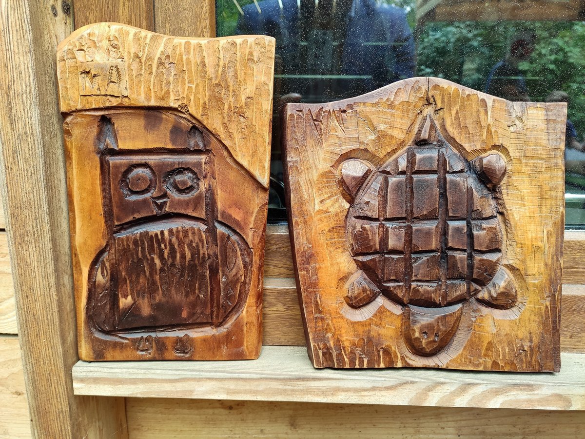 Dwie drewniane płaskorzeźby - z lewej wyrzeźbiona sowa, z prawej żółw.