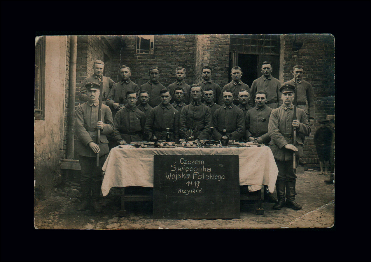 Widoczni na zdjęciu żołnierze pozują za zastawionym świątecznymi potrawami stołem. Poniżej na tablic